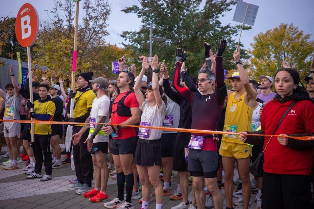 Au parc Jean-Drapeau à 8 h. Les coureur·euse·s de la vague B lèvent les bras, concentré·e·s, quelques instants avant le départ. Pour permettre à la foule de s’élancer dans de bonnes conditions, l’organisation a fait partir les athlètes par vagues successives, la première dès 7 h 45.